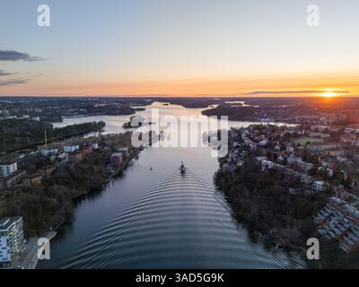 Coucher de soleil sur l'archipel de Stockholm, Suède, vue aérienne, avec des maisons sur le front de mer, bateau passant Banque D'Images