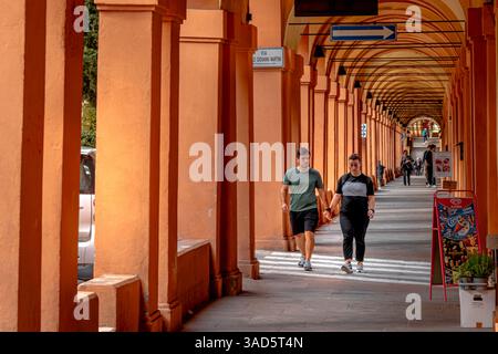 Un couple marchant la main le long de l'élégant portique de via Saragozza à Bologne, Italie Banque D'Images