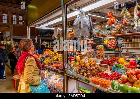 Une femme achetant des fruits à un étal de marché à côté Mercato delle Erbe un marché alimentaire couvert dans le centre de Bologne, en Italie Banque D'Images