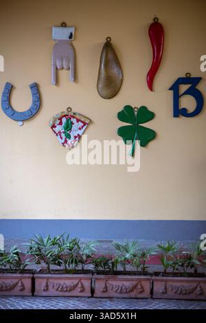Collection de charmes porte-bonheur italiens sur un mur à Turin, avec des symboles traditionnels comme un fer à cheval, une corne et un trèfle à quatre feuilles. Superstitieux d Banque D'Images