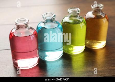 Bouteilles de parfum avec des huiles aromatiques sur fond en bois, gros plan Banque D'Images