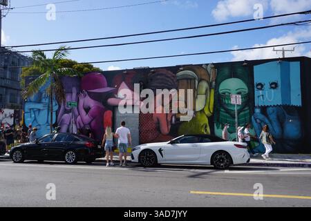 Les touristes font la queue aux emblématiques peintures murales en plein air de Wynwood Walls et à la galerie de graffitis par une journée ensoleillée à Miami, en Floride. Banque D'Images