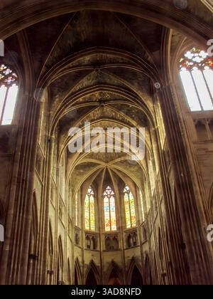 Une vue imprenable sur l'intérieur d'une grande cathédrale, présentant des arches complexes et de beaux vitraux qui illuminent l'espace avec c Banque D'Images