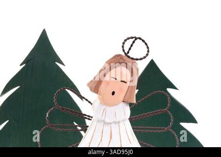 Ange en bois isolé devant les arbres de Noël. Arbre de Noël en bois avec gardien de Noël mignon. Design minimaliste. Décoration de saison des fêtes ou célébrité Banque D'Images