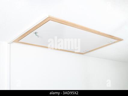 Trappe de grenier fermée ou porte de loft dans le plafond. Porte de grenier située dans l'escalier du bâtiment. Utilisé pour accéder à un loft, un espace de stockage ou un grenier. Mise au point sélective. Banque D'Images
