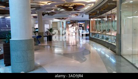 Un intérieur spacieux de centre commercial avec une architecture moderne, des sols en marbre poli et un éclairage élégant. La zone est principalement vide avec quelques dec Banque D'Images