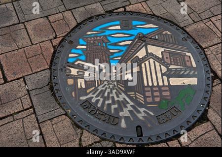 Art coloré de couverture de trou d'homme à Kawagoe, Saitama montrant des bâtiments d'entrepôt historiques dans le quartier des entrepôts, y compris le célèbre clocher, au Japon. Banque D'Images