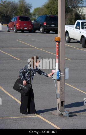 Apr 10, 2008 - Dallas, Texas, États-Unis - femme d'affaires solitaire sur le chemin de sa voiture dans un parking déserté cherche la sécurité de la boîte d'appel de sécurité avec un homme suspect dans le lot (image de crédit : Ed Lallo/ZUMAPRESS.com) Banque D'Images