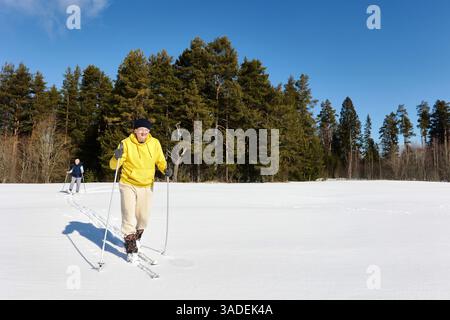 Mari et femme d'âge moyen se livrent au ski de fond, glissant à travers un champ de neige ouvert avec concentration et énergie, profitant d'activités de plein air ensemble. Banque D'Images