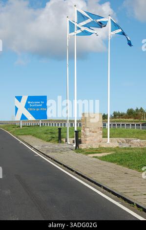 La frontière écossaise sur l'A1 dans le Northumberland est marquée par des drapeaux de St Andrew et une pierre de marquage. Banque D'Images