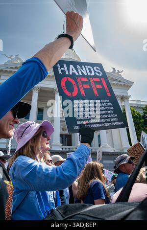 Une femme tient une pancarte détaillée Hands Off devant le Capitole lors de la manifestation Hands-Off 50501, qui s'est tenue au centre-ville sur le site du Capitole. Banque D'Images