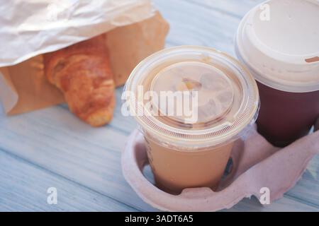 Petit déjeuner avec boisson glacée et croissant chaud sur table en bois Banque D'Images