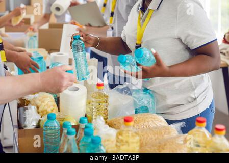Divers bénévoles regroupent le tri des dons de denrées alimentaires dans des boîtes en carton pour la collecte de nourriture caritative Banque D'Images
