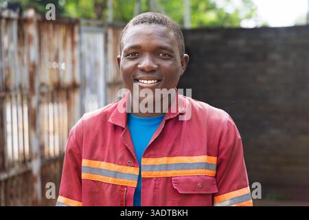 portrait unique village africain heureux homme ouvrier souriant en vêtements de travail debout dans la cour, jeune homme Banque D'Images