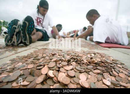 08 juil. 2008 - Fort Scott, Kansas, États-Unis - deux membres de l'équipe de football du Fort Scott Community College alignent des sous dans le stationnement de l'école intermédiaire de Fort Scott mardi soir. Mardi, les volontaires ont commencé à aligner le premier des près de 3,5 millions de pièces pour tenter d'établir un nouveau record du Livre Guiness des records du monde d'ici vendredi. Une fois terminée, la chaîne de sous s'étendra sur plus de 40 milles de longueur et établira un nouveau record et remplira complètement le stationnement. L’équipe d’activités jeunesse, le groupe responsable du projet et le groupe de bénévoles ont amassé les pièces dans le cadre d’un fundra Banque D'Images