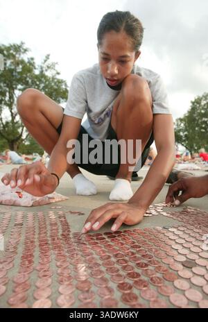 08 juil. 2008 - Fort Scott, Kansas, États-Unis - Jolee Sharp aligne des sous dans le stationnement de l'école intermédiaire de Fort Scott mardi soir. Mardi, les volontaires ont commencé à aligner le premier des près de 3,5 millions de pièces pour tenter d'établir un nouveau record du Livre Guiness des records du monde d'ici vendredi. Une fois terminée, la chaîne de sous s'étendra sur plus de 40 milles de longueur et établira un nouveau record et remplira complètement le stationnement. L’équipe d’activités jeunesse, le groupe responsable du projet et le groupe de bénévoles ont amassé les pièces dans le cadre d’une collecte de fonds pour un parc de 4 millions de dollars. Les organisateurs ont dit le p Banque D'Images