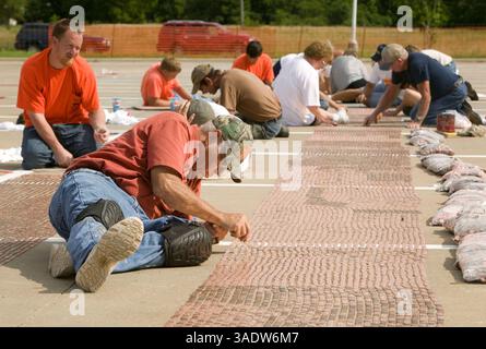 08 juil. 2008 - Fort Scott, Kansas, États-Unis - Un bénévole place des pièces de monnaie dans le stationnement de l'école intermédiaire de Fort Scott mardi soir. Mardi, les volontaires ont commencé à aligner le premier des près de 3,5 millions de pièces pour tenter d'établir un nouveau record du Livre Guiness des records du monde d'ici vendredi. Une fois terminée, la chaîne de sous s'étendra sur plus de 40 milles de longueur et établira un nouveau record et remplira complètement le stationnement. L’équipe d’activités jeunesse, le groupe responsable du projet et le groupe de bénévoles ont amassé les pièces dans le cadre d’une collecte de fonds pour un parc de 4 millions de dollars. Les organisateurs ont dit le p Banque D'Images