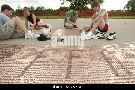 08 juil. 2008 - Fort Scott, Kansas, États-Unis - des diplômés récents du secondaire alignent des sous dans le stationnement de l'école intermédiaire de Fort Scott mardi soir. Mardi, les volontaires ont commencé à aligner le premier des près de 3,5 millions de pièces pour tenter d'établir un nouveau record du Livre Guiness des records du monde d'ici vendredi. Une fois terminée, la chaîne de sous s'étendra sur plus de 40 milles de longueur et établira un nouveau record et remplira complètement le stationnement. L’équipe d’activités jeunesse, le groupe responsable du projet et le groupe de bénévoles ont amassé les pièces dans le cadre d’une collecte de fonds pour un parc de 4 millions de dollars. Orgue Banque D'Images