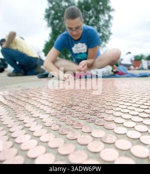 08 juil. 2008 - Fort Scott, Kansas, États-Unis - Un bénévole de Fort Scott place des pièces de monnaie dans le stationnement de l'école intermédiaire de Fort Scott mardi soir. Mardi, les volontaires ont commencé à aligner le premier des près de 3,5 millions de pièces pour tenter d'établir un nouveau record du Livre Guiness des records du monde d'ici vendredi. Une fois terminée, la chaîne de sous s'étendra sur plus de 40 milles de longueur et établira un nouveau record et remplira complètement le stationnement. L’équipe d’activités jeunesse, le groupe responsable du projet et le groupe de bénévoles ont amassé les pièces dans le cadre d’une collecte de fonds pour un parc de 4 millions de dollars. Organisateurs Banque D'Images