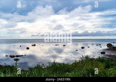 Un paysage serein avec un plan d'eau calme reflétant le ciel, entouré de rochers et de verdure luxuriante. La scène capture une atmosphère tranquille Banque D'Images