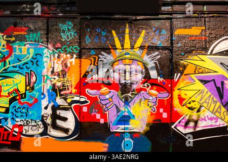Murale Street art dynamique avec des graffitis colorés mettant en valeur des formes et des dessins abstraits sur un mur de briques, représentant la créativité et la culture urbaines Banque D'Images