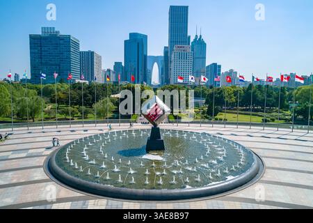 Suzhou, Chine - 06 septembre 2020 : paysage urbain de Suzhou avec des bâtiments modernes et affichage de drapeau avec une fontaine décorative au premier plan Banque D'Images