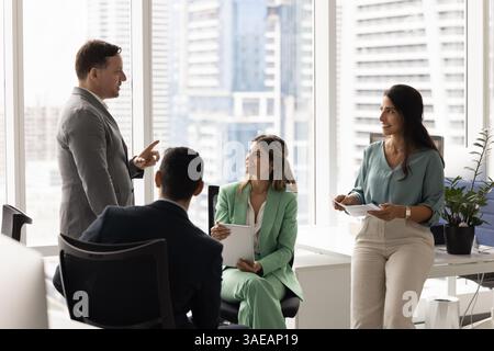 Collègues d'affaires positifs et diversifiés écoutant l'offre du chef d'équipe Banque D'Images