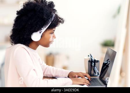 Preteen Girl faisant des devoirs sur ordinateur portable apprentissage en ligne à partir de la maison Banque D'Images