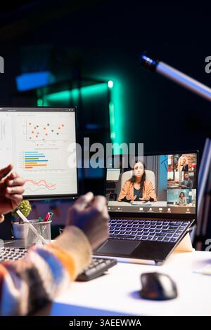 Brandissant de son appartement, homme noir utilisant un ordinateur portable pour participer à des réunions en ligne. Les indépendants masculins utilisent la technologie sans fil pour la visioconférence avec leurs collègues afin de discuter du travail à distance. Banque D'Images