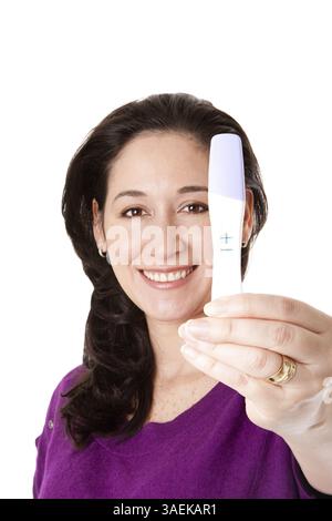 Belle femme souriante heureuse découvre qu'elle est enceinte d'un bébé avec un test de grossesse positif tenu dans sa main, isolé, New York, USA, North AME Banque D'Images
