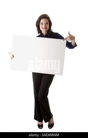 Heureux souriant belle jeune femme étudiante en affaires brune caucasienne debout tenant un tableau blanc blanc et pointant vers elle, isolée, New York, U. Banque D'Images