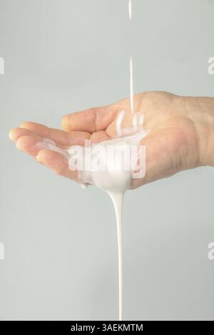 Gros plan de la main de la femme versant de la crème blanche Banque D'Images