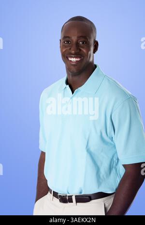 Beau homme d'affaires afro-américain heureux souriant, portant un polo bleu, les mains dans la poche, debout, isolé, New York, États-Unis, Amérique du Nord Banque D'Images