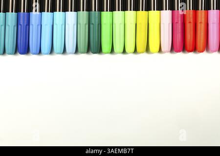 Marqueurs colorés placés dans une rangée sur un fond blanc avec espace de copie Banque D'Images