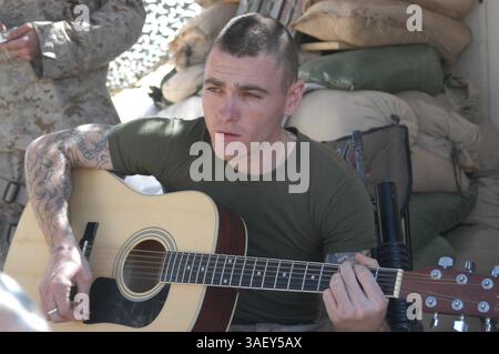 20 mars 2005 ; Camp Hurricane point, Irak ; lance Cpl. JOSH R. BARFIELD, assaillant, 1er peloton, 1re escouade, compagnie A, 1st Battalion, 5th Marine Regiment, chante tout en jouant des paroles complémentaires sur une guitare acoustique. Glendora, Calif., 23 ans, est le chanteur principal du groupe de metal Blue Collar, qui a actuellement un CD de démo. Son groupe a également joué un concert à Newport Beach, Calif. Il n’a pas encore atteint la renommée internationale, mais il a un certain nombre de fans dans son unité. En attendant, sa scène est une chaise pliante entourée de sacs de sable. Il se produit souvent pour son camarade g. Banque D'Images