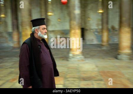 12 décembre 2004 ; Bethléem, CISJORDANIE ; Un prêtre orthodoxe grec marche dans l'église de la Nativité de Bethléem. Le ruch est construit au sommet de la grotte où la plupart des traditions croient que Jésus est né. On croit traditionnellement que la grotte est l'endroit où Jésus est né, et l'église a été construite au-dessus d'elle. Avec moins de deux semaines avant Noël, les touristes et les pilgrammes commencent à retourner à l'église pendant l'accalmie actuelle. Les commerçants espèrent que cette année sera nettement meilleure que les quatre dernières, depuis le début du soulèvement actuel. Banque D'Images