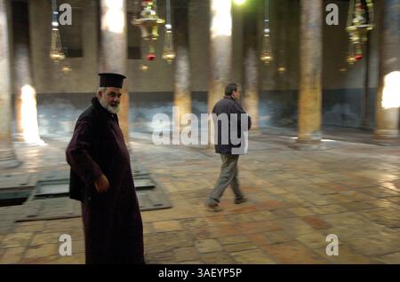 12 décembre 2004 ; Bethléem, CISJORDANIE ; Un prêtre orthodoxe grec marche dans l'église de la Nativité de Bethléem. Le ruch est construit au sommet de la grotte où la plupart des traditions croient que Jésus est né. On croit traditionnellement que la grotte est l'endroit où Jésus est né, et l'église a été construite au-dessus d'elle. Avec moins de deux semaines avant Noël, les touristes et les pilgrammes commencent à retourner à l'église pendant l'accalmie actuelle. Les commerçants espèrent que cette année sera nettement meilleure que les quatre dernières, depuis le début du soulèvement actuel. Banque D'Images