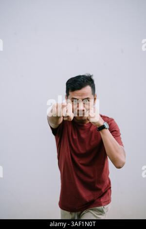 Homme dans une pose de combat avec les poings serrés, montrant la détermination et la préparation pour l'action ou la compétition Banque D'Images