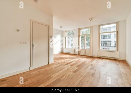 Spacieuse et bien éclairée, cette chambre dispose de grandes fenêtres qui apportent de la lumière naturelle, agrémentée d'un parquet chaleureux et d'un design minimaliste. Idéal pour diverses utilisations. Banque D'Images