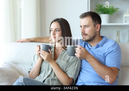 Couple détendu buvant du thé et se relaxant assis sur un canapé à la maison Banque D'Images