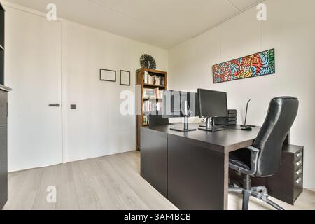Un bureau à domicile moderne et élégant avec un bureau en bois, une configuration informatique, des étagères et un décor mural artistique, créant un environnement de travail productif. Banque D'Images