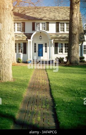 Maison blanche de deux étages avec volets sombres dans une longue pelouse verte Banque D'Images