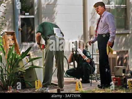TP.112207.- - LIVRER À :.Tampa.- -.10/21/2000.- -.Tampa.CAPTION INFO :. Les adjoints du shérif du comté de Hillsborough, de gauche à droite, le détective Mike Hurley, le détective de scène criminelle Lori Egan et le détective John King, à droite, vérifient la cour au 4217 Lakewood Dr, Seffner, samedi pour des preuves possibles en lien avec l'homicide multiple. Cinq corps ont été découverts au 4217 Lakewood Drive à Seffner après une confrontation policière avec Dexter Alonzo Levingston arrêté. Jusqu'à présent, Levingston a été accusé de trois chefs d'accusation de voies de fait graves découlant de l'impasse, mais n'a pas été accusé de c Banque D'Images
