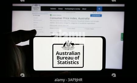 Stuttgart, Allemagne - 11-21-2024 : personne tenant un téléphone portable avec le logo de l'agence Australian Bureau of Statistics (ABS) sur l'écran en face de la page Web. Banque D'Images