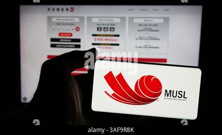 Stuttgart, Allemagne - 2024 : personne tenant un téléphone portable avec le logo de l'organisation Multi-State Lottery Association (MUSL) sur l'écran Banque D'Images