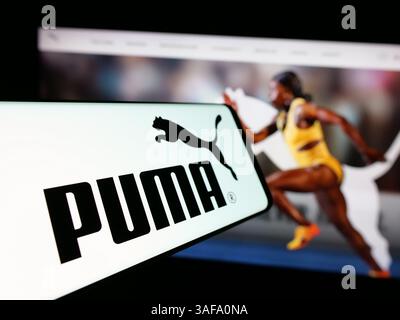 Stuttgart, Allemagne - 11-20-2024 : téléphone portable avec le logo de la société allemande de chaussures et de vêtements Puma se sur l'écran devant le site Web de l'entreprise. Banque D'Images