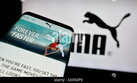 Stuttgart, Allemagne - 11-20-2024 : téléphone portable avec le site Web de la société allemande de chaussures et de vêtements Puma se sur l'écran devant le logo de l'entreprise. Banque D'Images