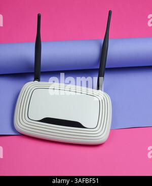 Routeur Wi-fi sur fond de papier enveloppé. Tendance aux couleurs pastel, nature morte minimaliste. Gadgets modernes. Vue de dessus Banque D'Images
