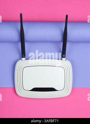 Routeur Wi-fi sur fond de papier enveloppé. Tendance aux couleurs pastel, nature morte minimaliste. Gadgets modernes. Vue de dessus Banque D'Images
