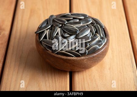 Les graines de tournesol noires dans un bol sur la table en bois Banque D'Images